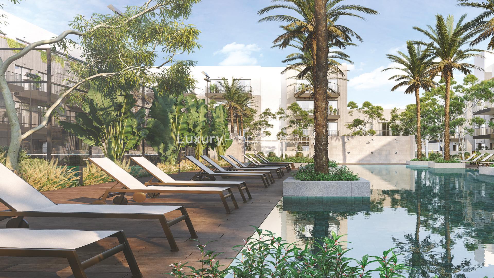 "Modern facade of Oakley Square Residences apartment in Jumeirah Village Circle, Dubai.",Poolside view at Oakley Square Residences, JVC, featuring sun loungers and lush greenery