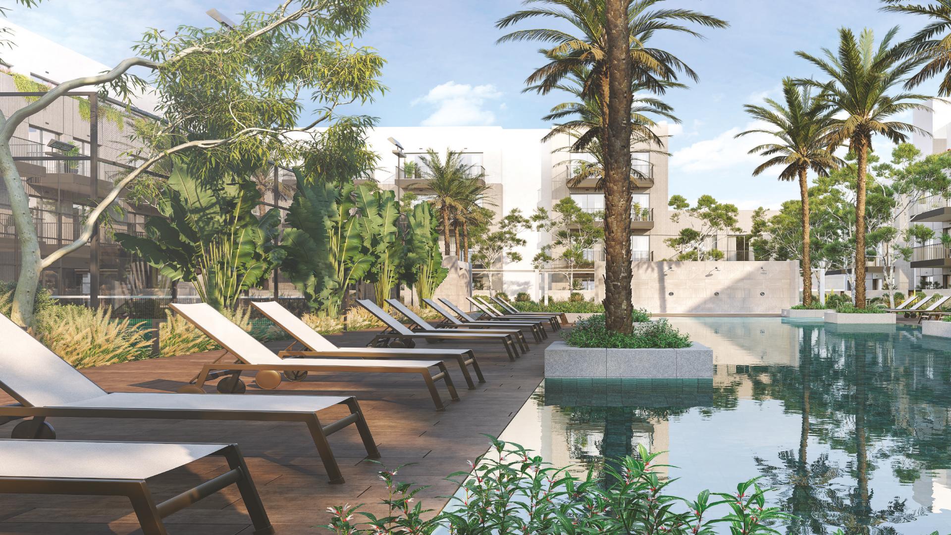 "Modern facade of Oakley Square Residences apartment in Jumeirah Village Circle, Dubai.",Poolside view at Oakley Square Residences, JVC, featuring sun loungers and lush greenery