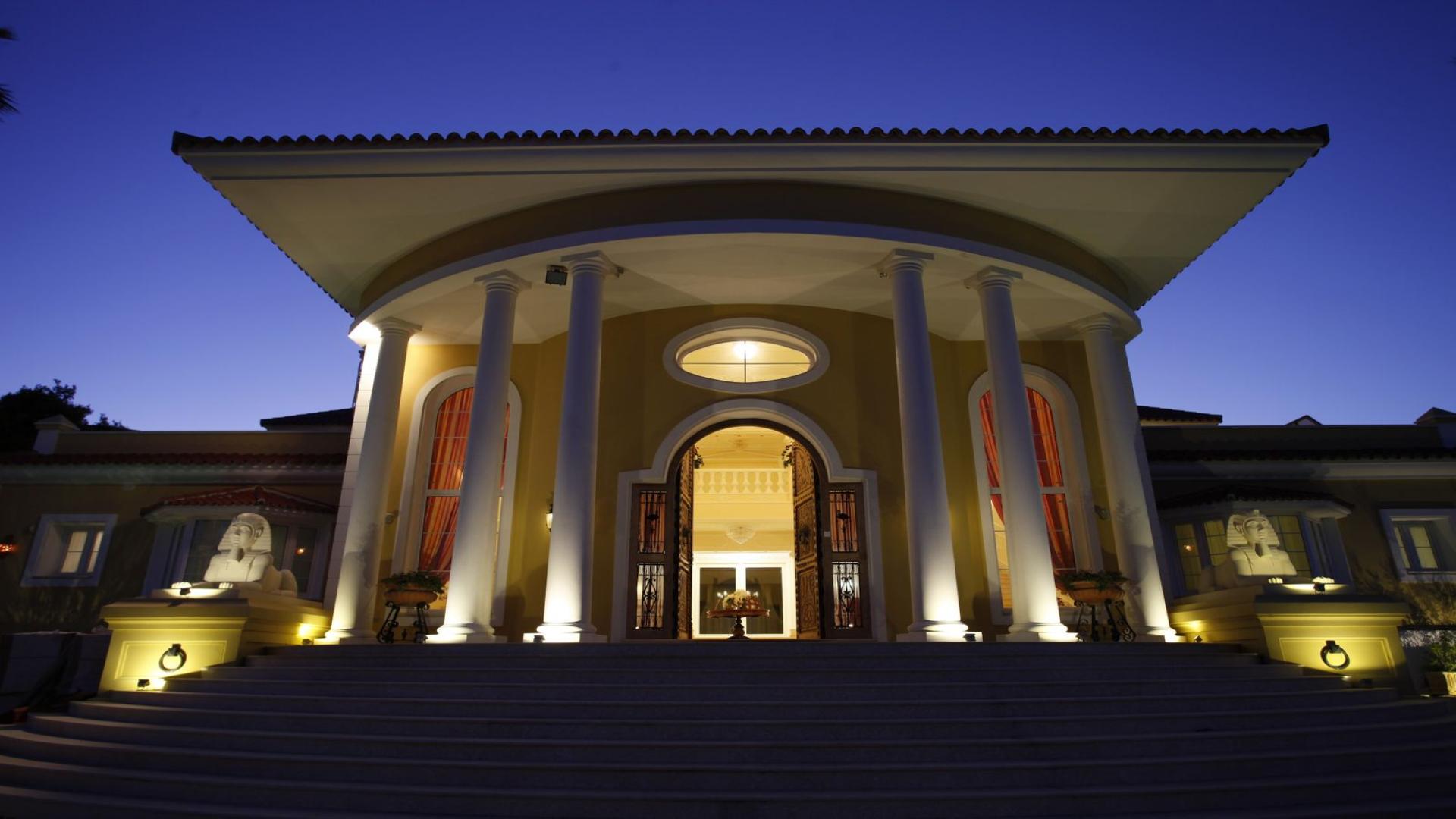 Elegant 6-bedroom villa exterior in Sotogrande, Spain with gated entrance and palm trees