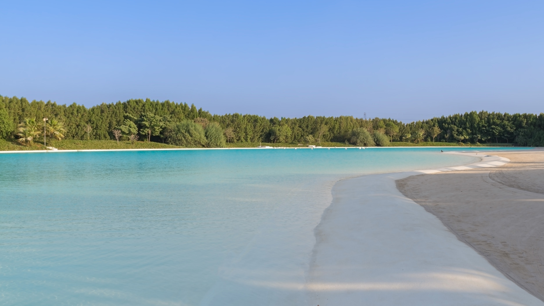 Alt text: "Stunning waterfront view of District One, MBR City skyline with lush greenery.",Triple-sized plot with stunning beachfront in MBR City, District One, for sale.