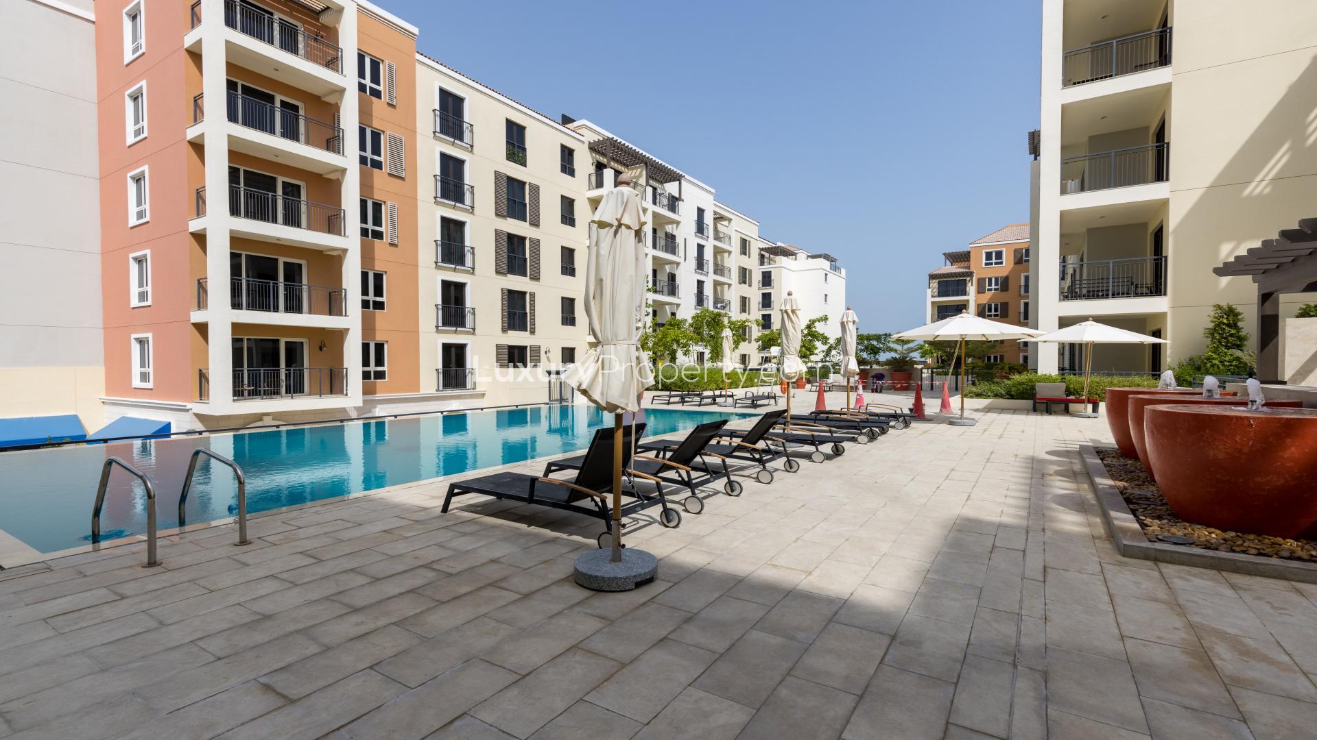 Outdoor pool area at beachfront residential plot in La Mer, Jumeirah, Dubai skyline in background