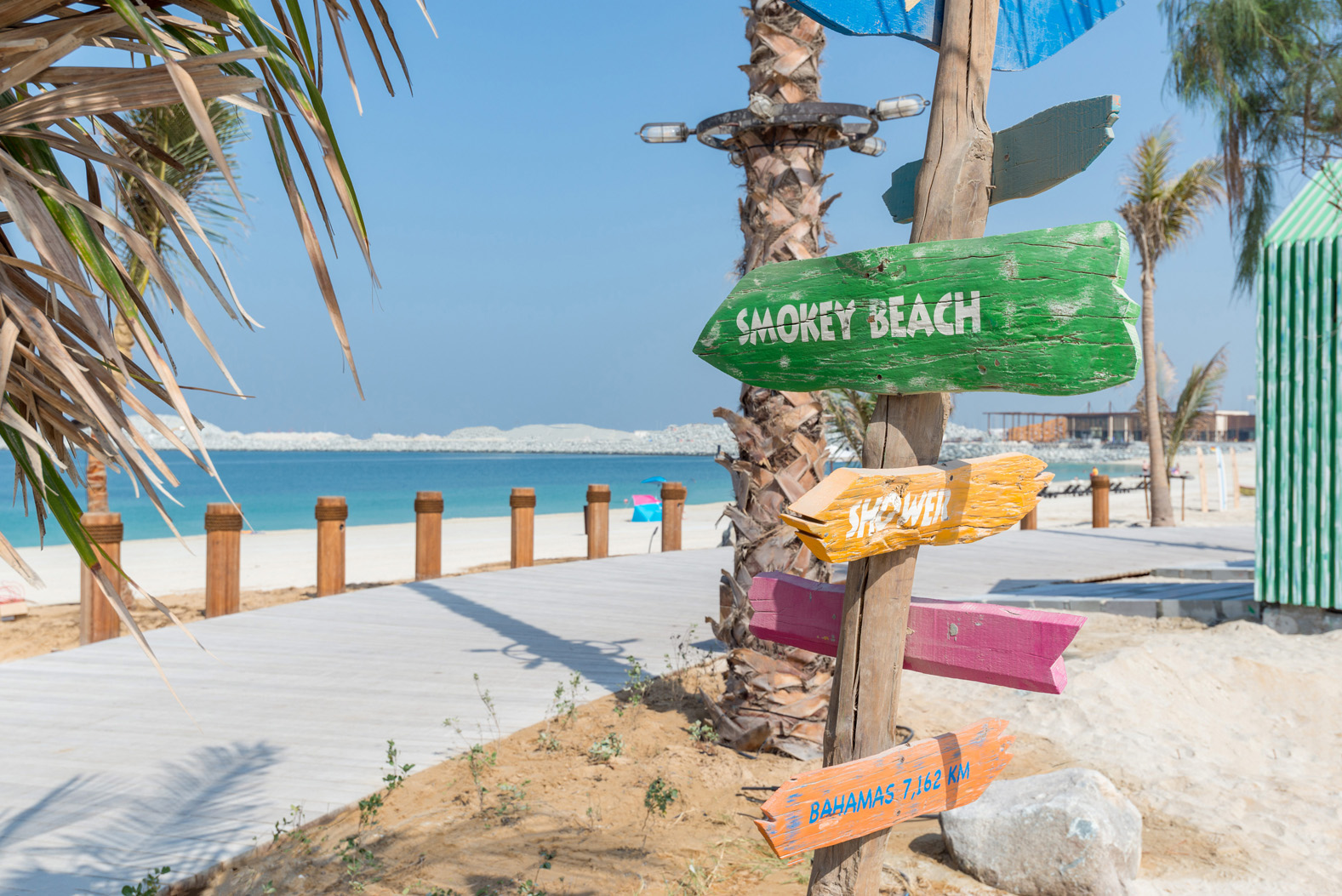 Colorful beach huts and signpost at La Mer South, Jumeirah, near the sea